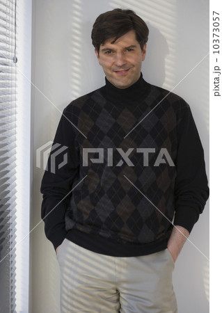 Man with hands in pockets next to window Man with hands in pockets next to window 10373057