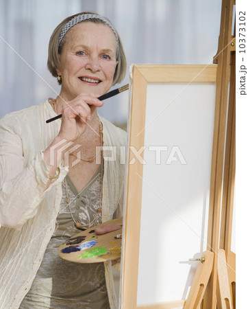 Senior woman painting on easel 10373102
