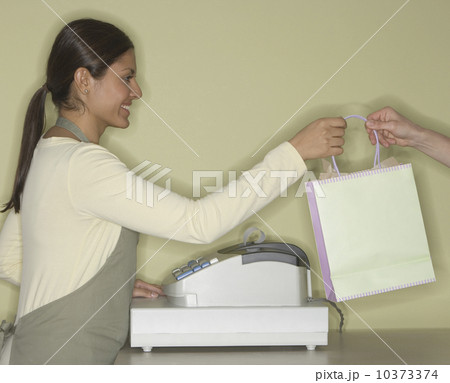 Indian female clerk handing shopping bag Indian female clerk handing shopping bag 10373374
