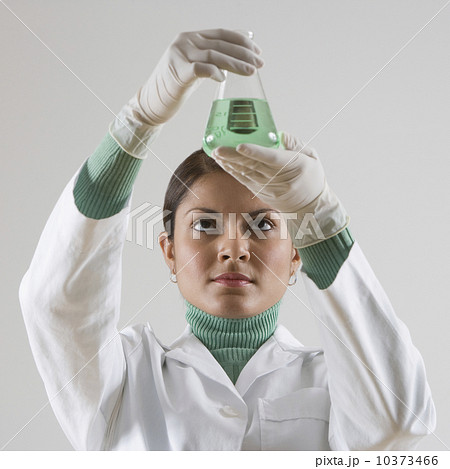Indian female scientist looking at beaker of liquid 10373466