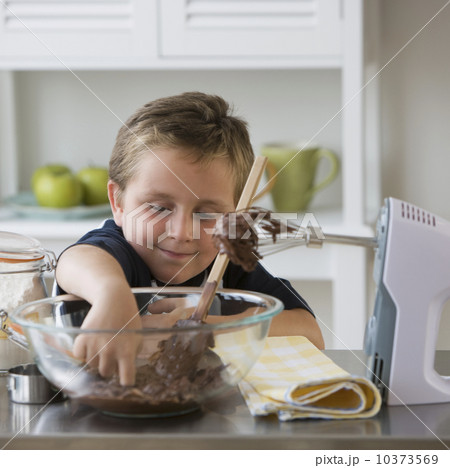Boy sticking finger into bowl of batter Boy sticking finger into bowl of batter 10373569