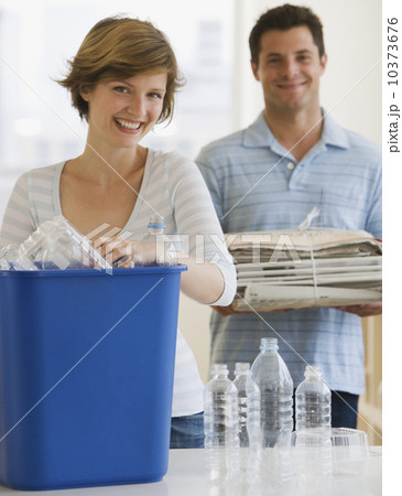 Couple recycling plastic and newspaper Couple recycling plastic and newspaper 10373676