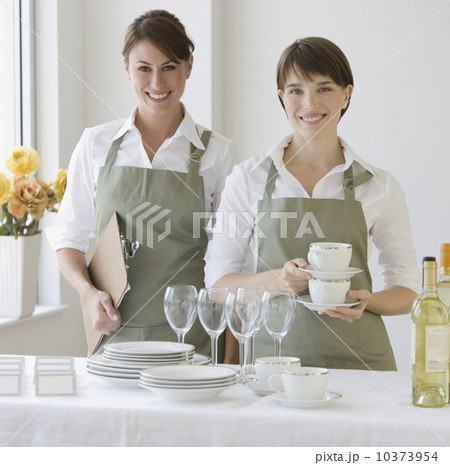 Two female caterers with dishware Two female caterers with dishware 10373954