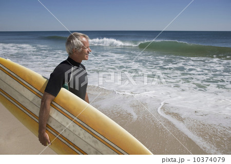 Man holding surfboard at beach Man holding surfboard at beach 10374079