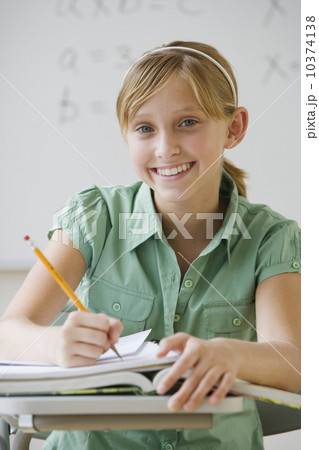 Teenaged girl writing at school desk 10374138
