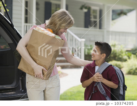 Mother holding groceries and smiling at son Mother holding groceries and smiling at son 10374205