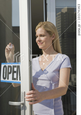 Woman hanging Open sign in doorway Woman hanging Open sign in doorway 10374363