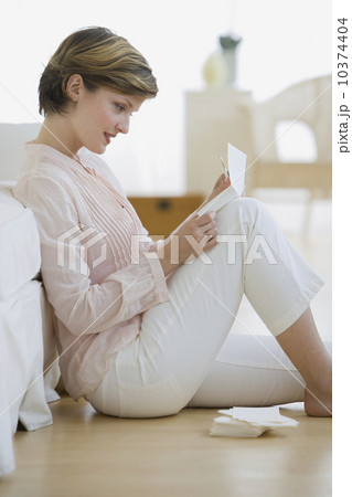 Woman reading mail on floor 10374404