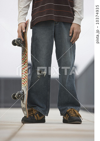 Teenaged boy holding skateboard 10374935