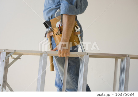 Man wearing tool belt and holding ladder 10375034