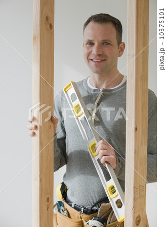 Male construction worker holding level tool 10375101