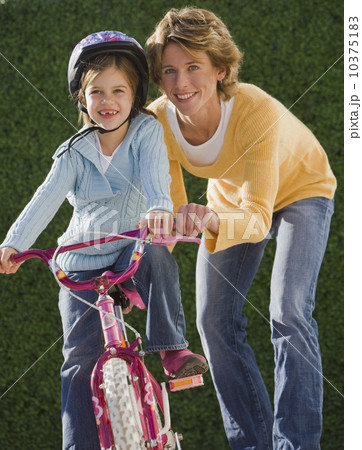 Mother helping daughter ride bicycle 10375183