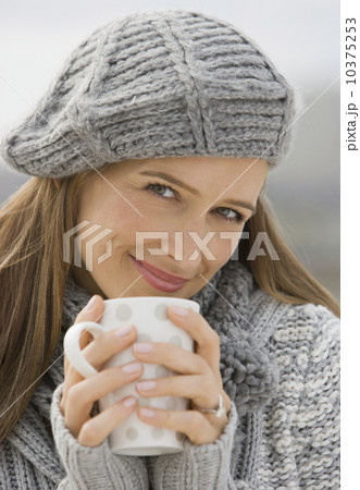 Woman in hat and sweater holding coffee mug 10375253