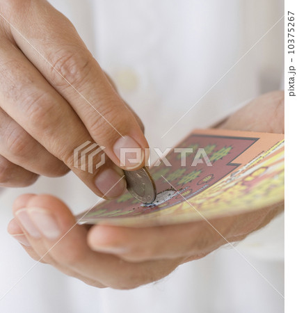 Man scratching lottery card with coin Man scratching lottery card with coin 10375267