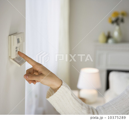 Woman adjusting digital thermostat 10375289