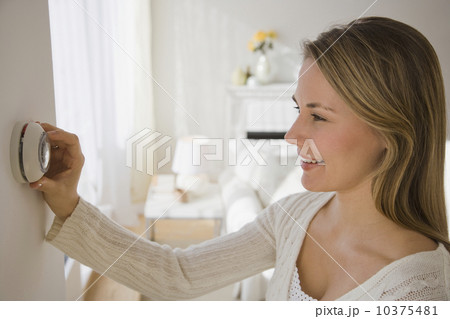 Woman adjusting thermostat Woman adjusting thermostat 10375481