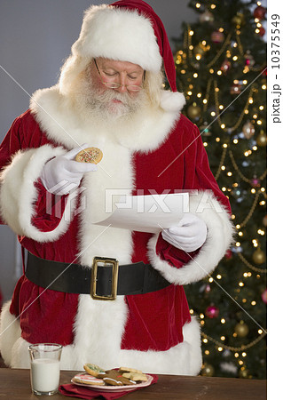 Santa Claus reading letter and eating cookies 10375549