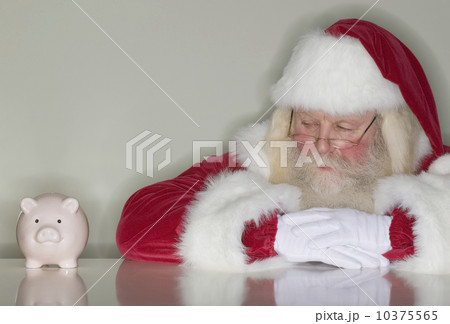 Santa Claus looking at piggy bank 10375565