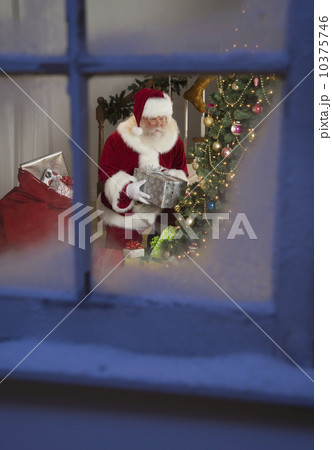 Santa Claus leaving gifts under Christmas tree 10375746