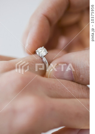 Man putting engagement ring on woman’s finger 10375956