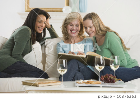 Multi-ethnic women looking at photo album 10376263