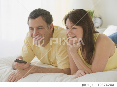 Couple pointing remote control on bed 10376288