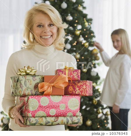 Senior woman holding stack of Christmas gifts 10376343