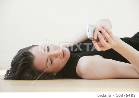 Woman lying on floor using pda, studio shot 10376485