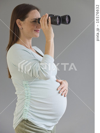 Pregnant Hispanic woman looking through binoculars Pregnant Hispanic woman looking through binoculars 10376632