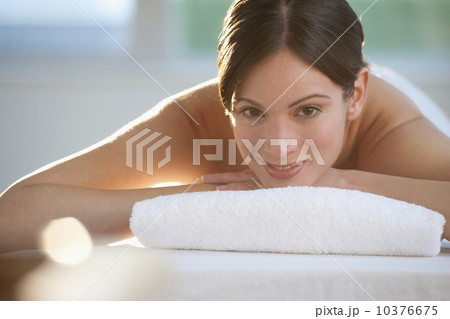 Mid-adult woman lying on massage table with candle in foreground Mid-adult woman lying on massage table with candle in foreground 10376675