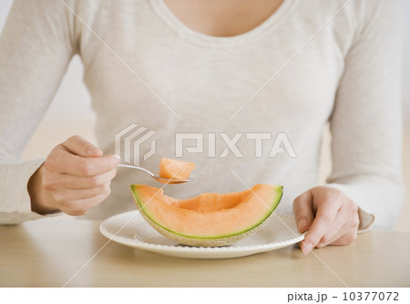 Woman eating melon wedge Woman eating melon wedge 10377072