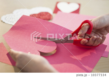 Woman cutting out heart in paper, close-up 10377334