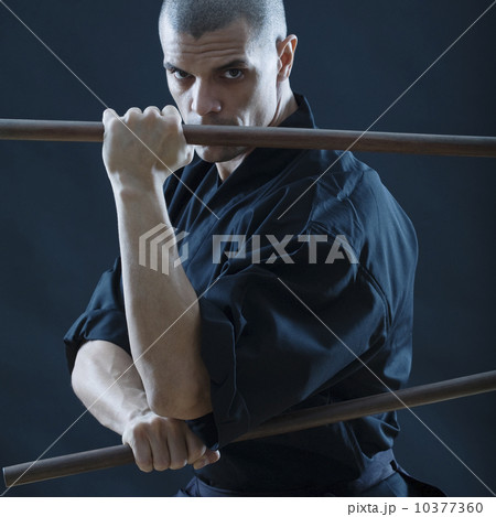 Hispanic male holding sticks in fighting stance Hispanic male holding sticks in fighting stance 10377360