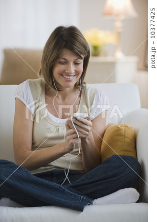 Woman sitting on sofa and listening to mp3 player 10377425