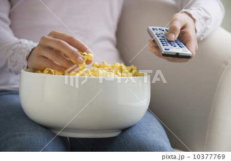 Close up of woman with remote control and bowl of popcorn Close up of woman with remote control and bowl of popcorn 10377769