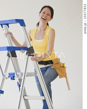 Woman wearing tool belt climbing ladder Woman wearing tool belt climbing ladder 10377852