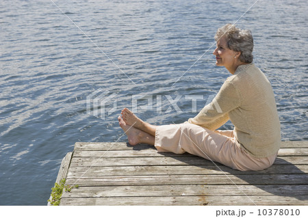 Senior woman sitting on dock Senior woman sitting on dock 10378010