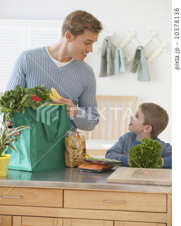 Father and son unpacking groceries 10378136