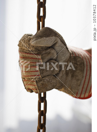 Close up of gloved hand holding chain 10378412