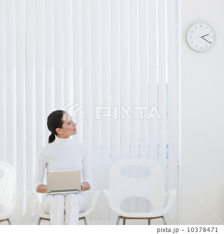 Businesswoman looking at clock in waiting room Businesswoman looking at clock in waiting room 10378471