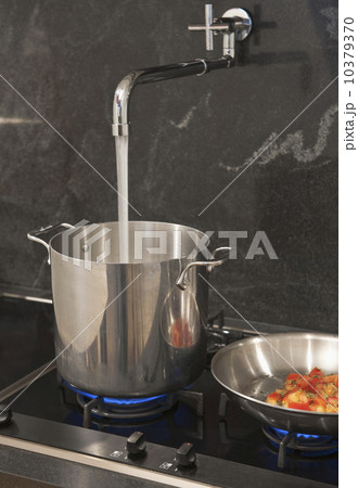 Water pouring from tap into pot 10379370