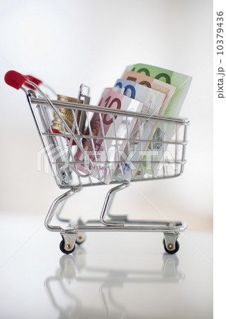 A miniature shopping cart with bank notes and coins A miniature shopping cart with bank notes and coins 10379436