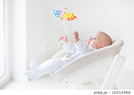 Cute newborn baby boy watching a colorful mobile toy sitting in Cute newborn baby boy watching a colorful mobile toy sitting in 10414966