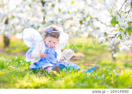 Curly toddler girl in fairy costume playing in fruit garden 10414990