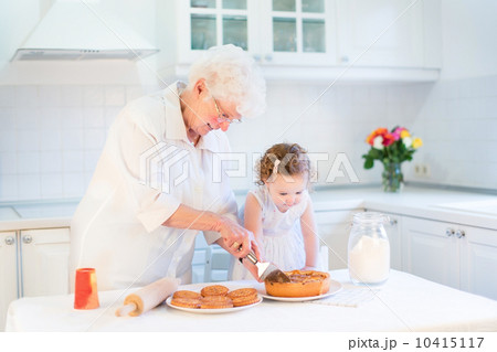 Loving grandmother baking an apple pie with her adorable toddler Loving grandmother baking an apple pie with her adorable toddler 10415117