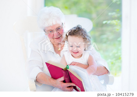 Beautiful senior lady reading a fairy tale book to her little gr Beautiful senior lady reading a fairy tale book to her little gr 10415279