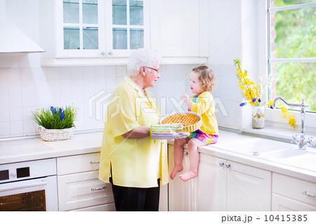 Happy grandmother and little girl baking a pie in a white kitche 10415385