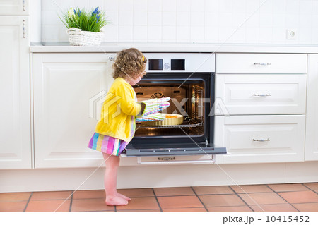 Toddler girl with an apple pie in the oven 10415452
