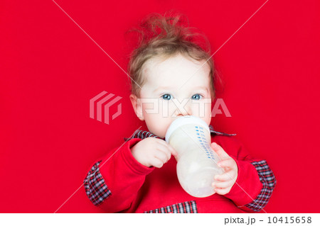 Cute little baby drinking milk on a red blanket Cute little baby drinking milk on a red blanket 10415658