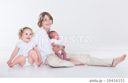 Portrait of three siblings, school age boy, his toddler sister a 10416151